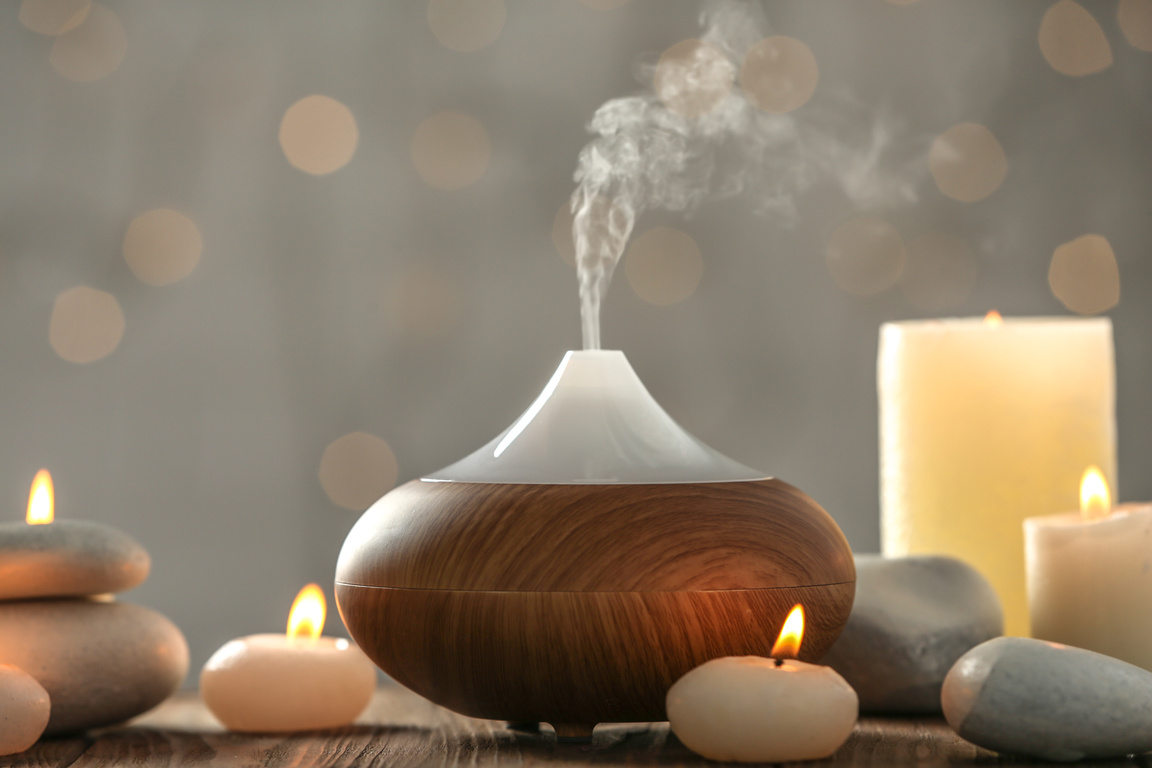 Aroma Oil Diffuser and Candles on Blurred Background